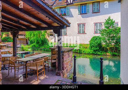 Street restaurant on wooden terrace with tables and chairs on quay of river Lauch canal in Little Venice la Petite Venise area in old town Colmar city Stock Photo