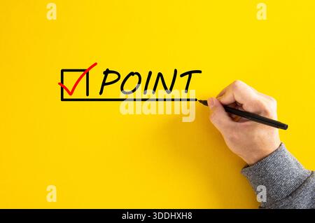 Hand completing a checklist item point with a red checkmark on a yellow background Stock Photo