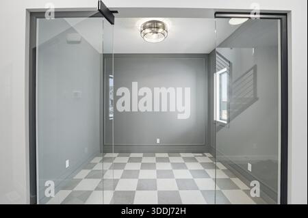 Room with a checkered floor and a glass door. The room is empty. There are no people or furniture in the room Stock Photo