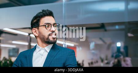 Man in Glasses Sits in Office Space While Looking out the Window During Daytime Work Hours Stock Photo