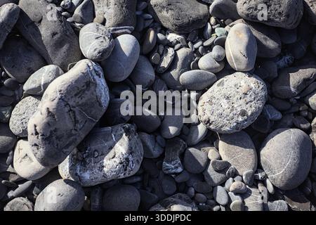 Pebbles on a beach in the sunlight seen from above and up close Stock Photo