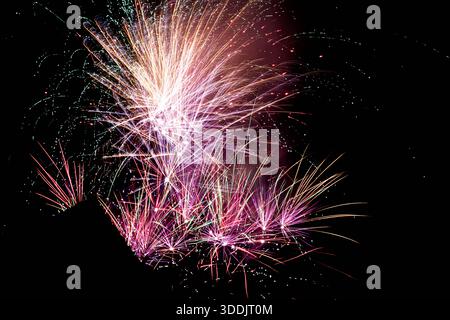 Long exposure abstract photograph of fireworks creating dense, colorful light trails with bright glowing bursts against a deep black night sky. Dynami Stock Photo