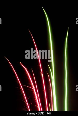 Red and Green Firework Light Trails Rising on Black Background Stock Photo