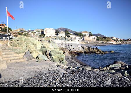 Rocks by the seashore and a platform with a red flag on it next to a small staircase Stock Photo