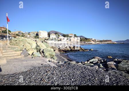 Rocks by the seashore and a platform with a red flag on it next to a small staircase Stock Photo