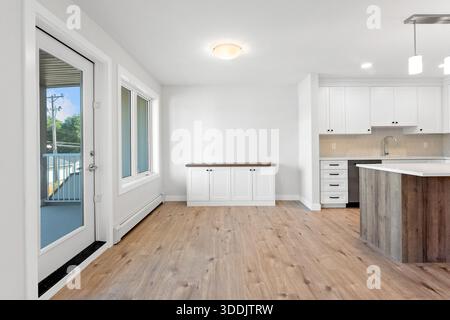Large open kitchen with a wooden island and a sink. The kitchen is very clean and bright, with a lot of natural light coming in through the windows Stock Photo