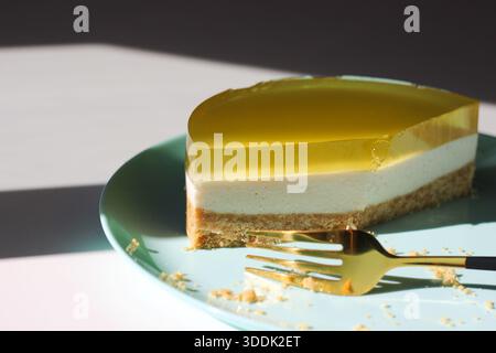 Cheesecake slice with fork on pastel plate, minimalist dessert composition Stock Photo