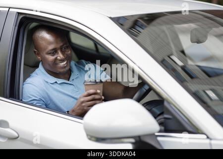 Relaxed black driver enjoying coffee break inside car Stock Photo