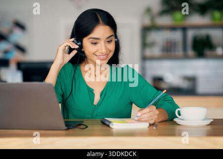 Pretty indian woman attending webinar, cafe interior, copy space Stock Photo