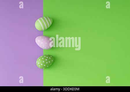 Spring composition with colorful Easter eggs on light green and purple background with copy space. Creative Easter concept. Festive holiday layout. Stock Photo