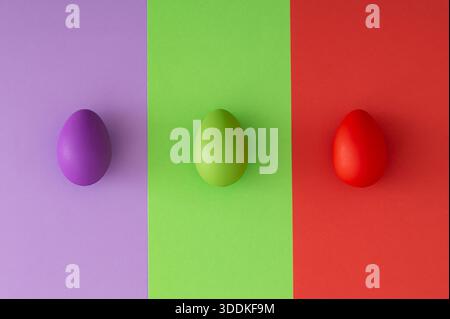Spring composition with colorful Easter eggs on green, purple and red background. Creative Easter concept. Festive holiday layout. Flat lay style. Stock Photo
