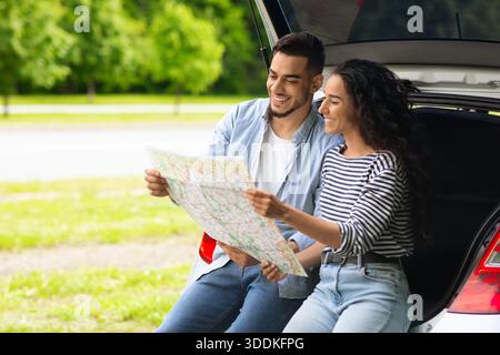 Loving middle-eastern couple watching map while having break, copy space Stock Photo