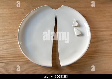 White plate broken into two parts, smart, modern desert plate from The White Company, on wooden kitchen table Stock Photo