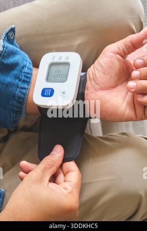 Man measuring blood pressure, focusing on cardiovascular health and hypertension prevention Stock Photo