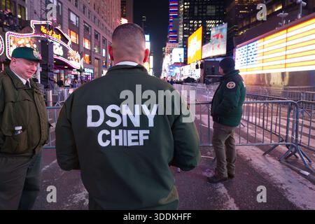 Two DSNY Chief workers stand in Times Square at night, with brightly lit billboards and metal barricades in the background. Stock Photo