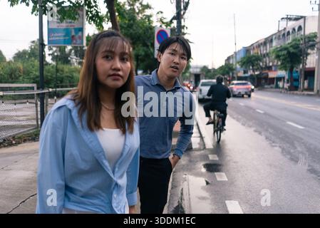 Young asian couple walking city street after rain on a wet day Stock Photo