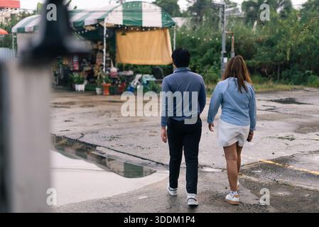 Couple walking on wet street enjoying outdoor market exploration Stock Photo