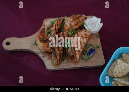 A serving of grilled chicken tacos on a rustic wooden board, garnished with cilantro and served with a side of crispy tortilla chips. Stock Photo