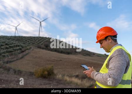 Engineer working outdoors with a drone controller, inspecting wind turbines at a renewable energy power station Stock Photo