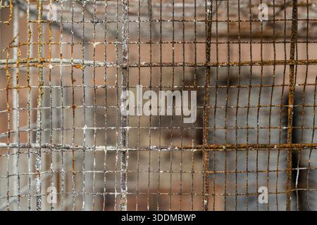 Rusty metal grid showing weathered, corroded mesh and square grate pattern; aged industrial texture with oxidation, decay and rough, grungy surface fo Stock Photo
