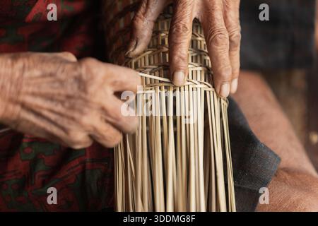 Senior Thai artisan weaving intricate bamboo basketry with precision Stock Photo