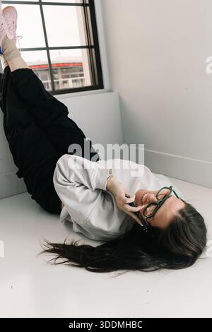 Woman relaxing on floor talking on smartphone Stock Photo