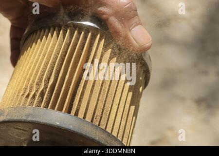 Hand holding old dirty air filter with dust particle showing neglected maintenance concept of car engine and mechanical service needing replacement pa Stock Photo