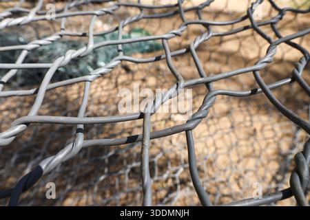 Close up detail of strong grey steel wire gabion mesh texture with stone rocks inside retaining wall structure displaying solid rough industrial safet Stock Photo