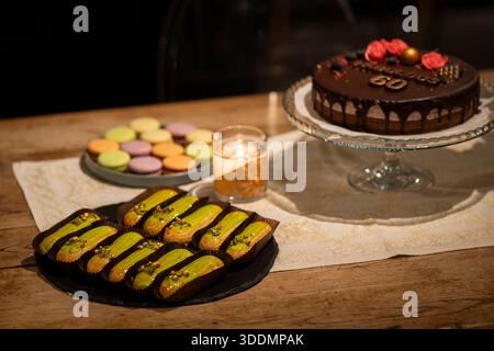 Pistachio-glazed éclairs served on a rustic table with candlelight at an elegant dessert buffet. Gourmet pistachio éclairs arranged for a luxury event. Stock Photo