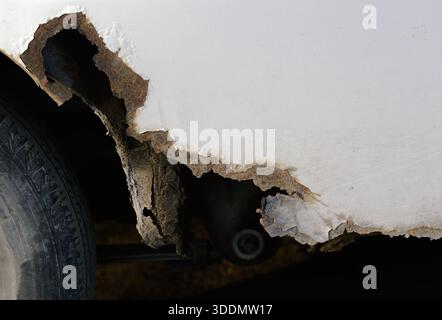 Severe rust damage and corrosion on white car fender. Stock Photo