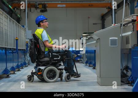 Man with disability on wheelchair working in modern industrial factory on a production line. Stock Photo