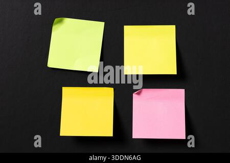 four blank colorful sticky notes on black wall. Template mock up Stock Photo