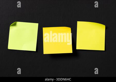 Three blank colorful sticky notes on black wall. Template mock up Stock Photo