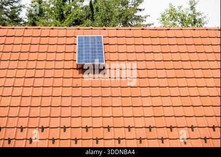 Solar panels installed on a roof of a residential home, red roof details lit by mornig sun Stock Photo