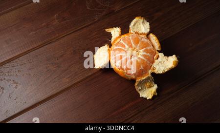 A vibrant orange sits open against a rich wooden surface, revealing its juicy segments. Stock Photo