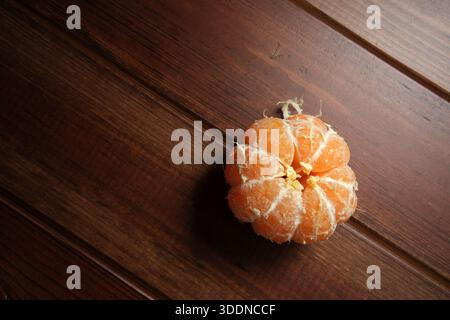 A bright orange citrus fruit sits calmly on a wooden surface, showcasing its texture. Stock Photo