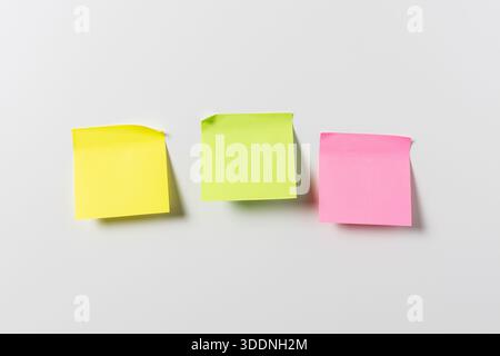 Three blank colorful sticky notes on white wall. Template mock up Stock Photo