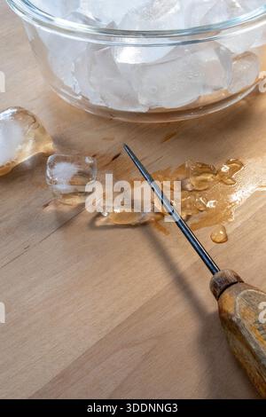 A weathered antique ice pick with a wooden handle on a cutting board with ice, 2025, United States Stock Photo