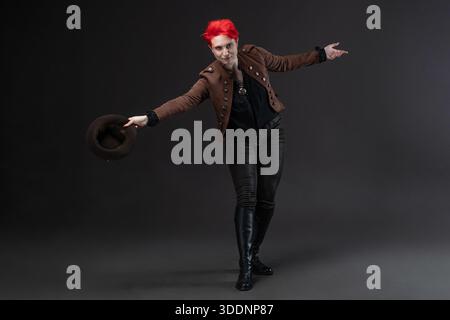 Red-haired lady in steampunk outfit featuring bowler hat with protective goggles, Makes a curtsy Stock Photo