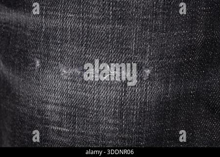 Close-up of Black Denim Fabric with Distressed Detail Stock Photo
