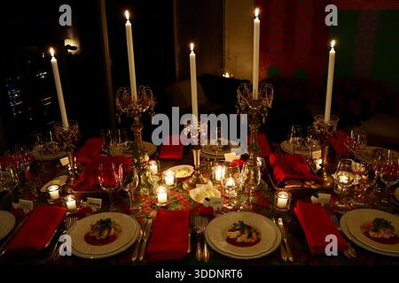 Christmas dinner table, table cloth, candle sticks with ornaments, red napkins, first course pre-plated, waiting for dinner guests to festive meal. Stock Photo