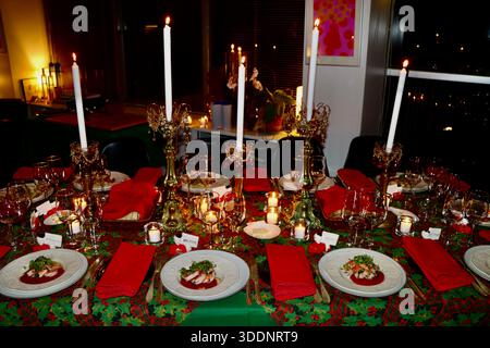Christmas dinner table, table cloth, candle sticks with ornaments, red napkins, first course pre-plated, waiting for dinner guests to festive meal. Stock Photo