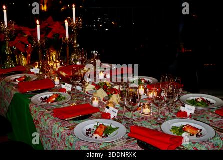 Christmas dinner table, table cloth, candle sticks with ornaments, red napkins, first course pre-plated, waiting for dinner guests to festive meal. Stock Photo