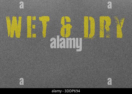 Wet and dry black fine grit sandpaper with the words wet and dry stencilled in yellow background backdrop. Stock Photo