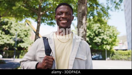 Black man, portrait and smile in city with low angle, space and positive for learning, scholarship or academics. Person, student and college pride Stock Photo