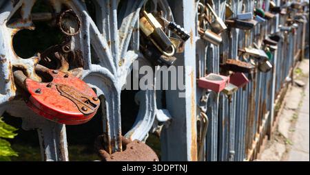 Many colorful love locks attached to a rusty iron bridge fence, symbolizing lasting commitment Stock Photo