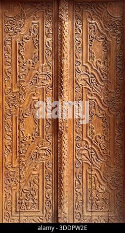Carved wooden door featuring hand-chiseled floral patterns and traditional architectural details Stock Photo