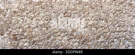 Rustic stone wall featuring ancient masonry with a textured surface, ideal for backgrounds Stock Photo