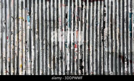 Corrugated metal wall showing weathered texture and layers of peeling posters Stock Photo