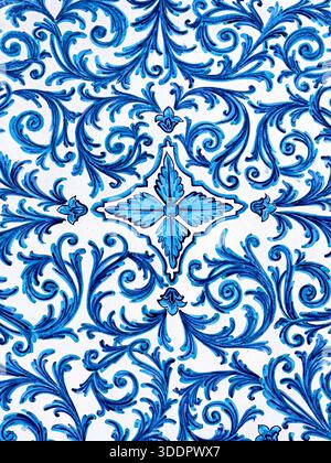 Repeating blue floral scrolls and leaves forming a traditional azulejo pattern on white ceramic Stock Photo